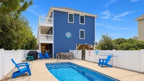 A residential property with a swimming pool, outdoor seating, and a two-story building.