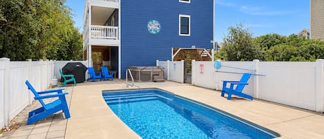 A residential property with a swimming pool, outdoor seating, and a two-story building.