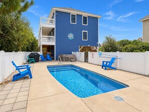A residential property with a swimming pool, outdoor seating, and a two-story building.