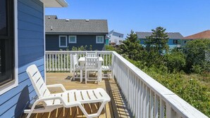 A wooden deck with white chairs and a table, surrounded by a white railing. - SEA GLASS SHACK -  4 bed, 2 bath, Pool, Hot Tub & Dogs Allowed (Corolla)