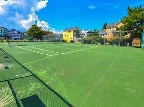 A tennis court surrounded by houses.
