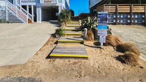 A pathway leading to a building with a staircase and a signboard.