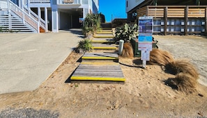 A pathway leading to a building with a staircase and a signboard.