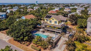 A two-story house with a pool, surrounded by trees and other houses. - Dunes Crest - Ocean and sound views in Duck, NC! 5 bed, 4.2 bath, pool, hot tub (Duck)