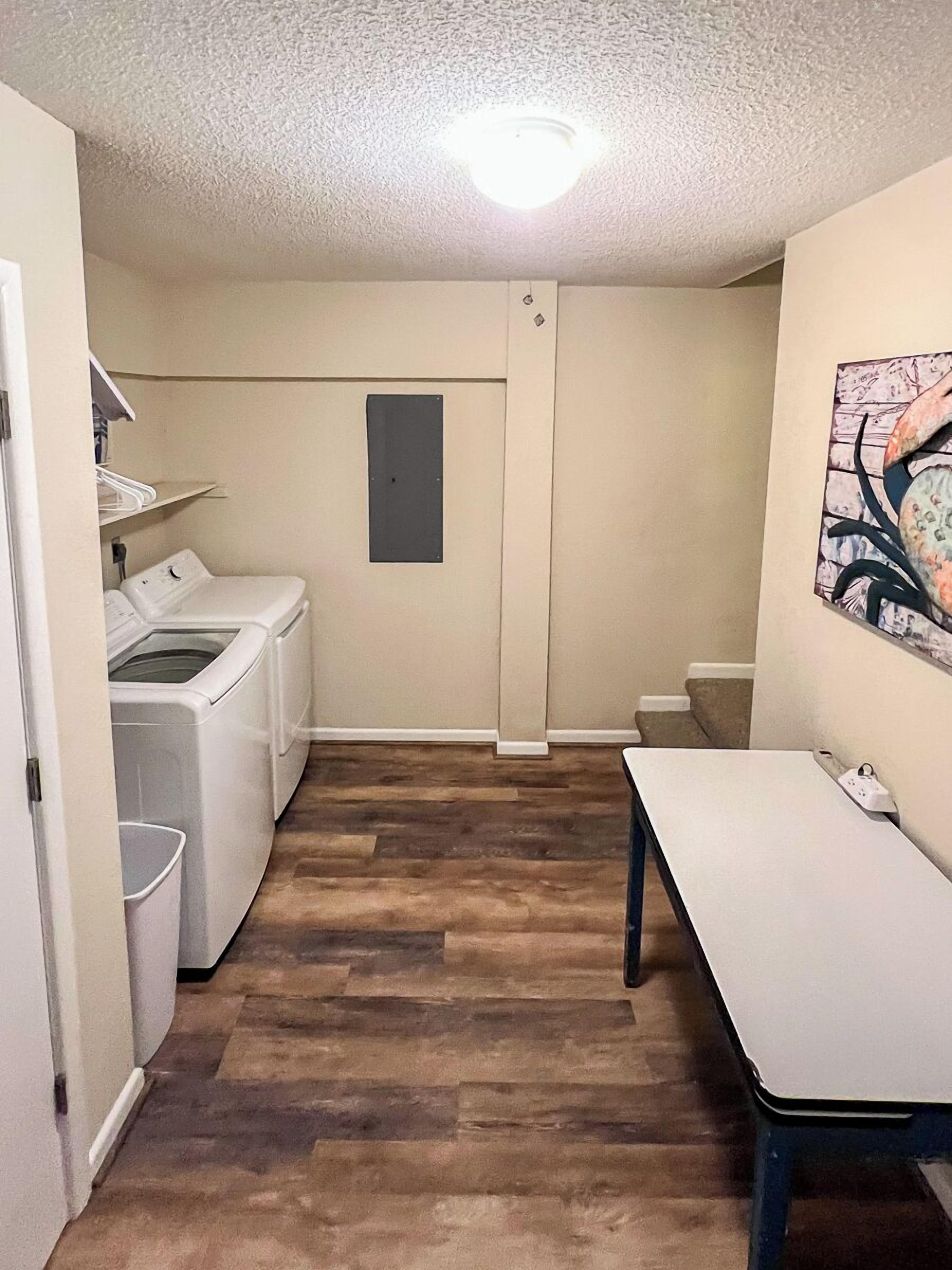 A laundry room with a washing machine, dryer, and a table with a power strip.