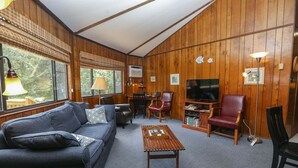 Una sala de estar acogedora con un sofá, sillas, una mesa de centro y un televisor.