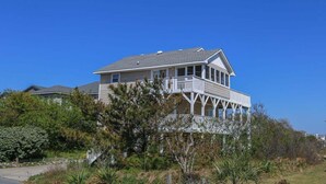 Une maison à deux étages avec un balcon, entourée de verdure.