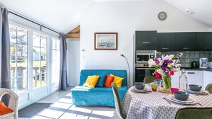 Ein heller Wohnbereich mit Sofa, Esstisch und einer Küche im Hintergrund.