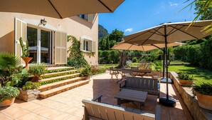 Une terrasse avec des meubles d’extérieur, une pergola et des plantes en pot.