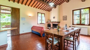 A spacious dining area with a wooden table and chairs, a fireplace, and large windows. - Apartment 'Il Covone' with Shared Pool, Shared Terrace and Wi-Fi (Rapolano Terme)
