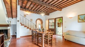 A dining area with a wooden table and chairs, a fireplace, and a staircase leading to another room. - Apartment 'La Lollaia' with Shared Pool, Shared Terrace and Wi-Fi (Rapolano Terme)