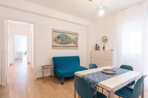 Un salon moderne avec un canapé, une table à manger et un tableau représentant un poisson accroché au mur.