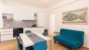 A modern kitchen with white cabinets, a patterned backsplash, and a dining area with a table and chairs. - Apartment 'Capitan Trinchetto Risacca' with Balcony and Wi-Fi (Trapani)