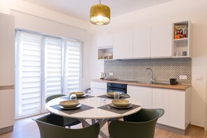 A modern kitchen with a dining table, chairs, and a hanging light fixture.