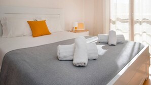A hotel room with a bed, a nightstand, a window with curtains, and a view of the outside. - Apartment 'Borealis  - Nazaré' with Sea View, Shared Terrace and Wi-Fi (Nazaré)