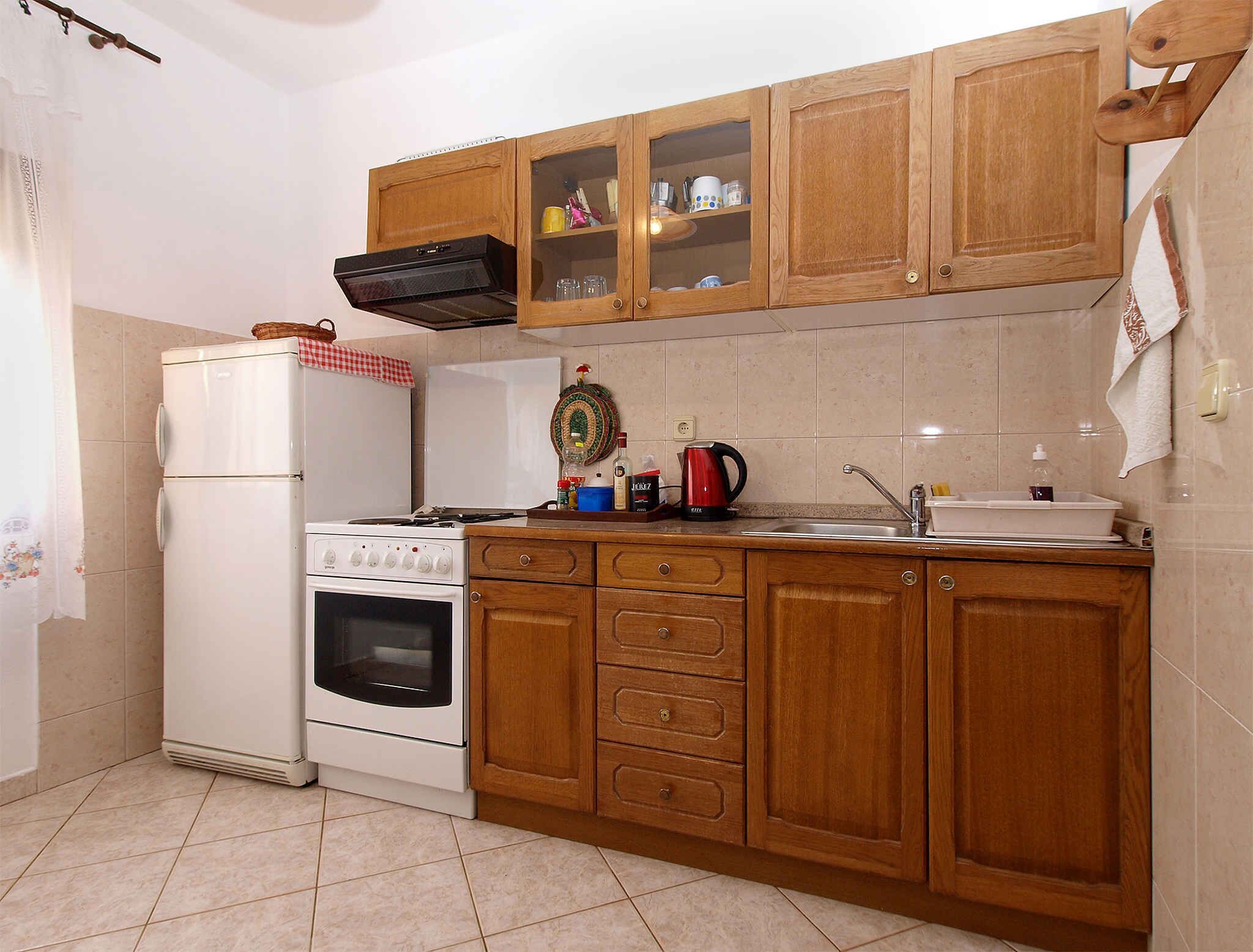Una cocina con armarios de madera, un refrigerador blanco, una estufa y un lavamanos.