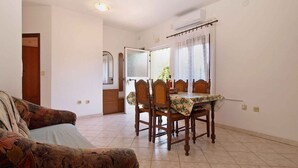 A dining area with a table set for four, a wooden chair, and a patterned sofa.