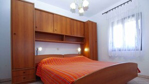 A bedroom with a wooden bed, a wardrobe, and a window with curtains.