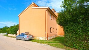 A two-story building with a beige exterior, a parked car in front, and a well-maintained lawn.
