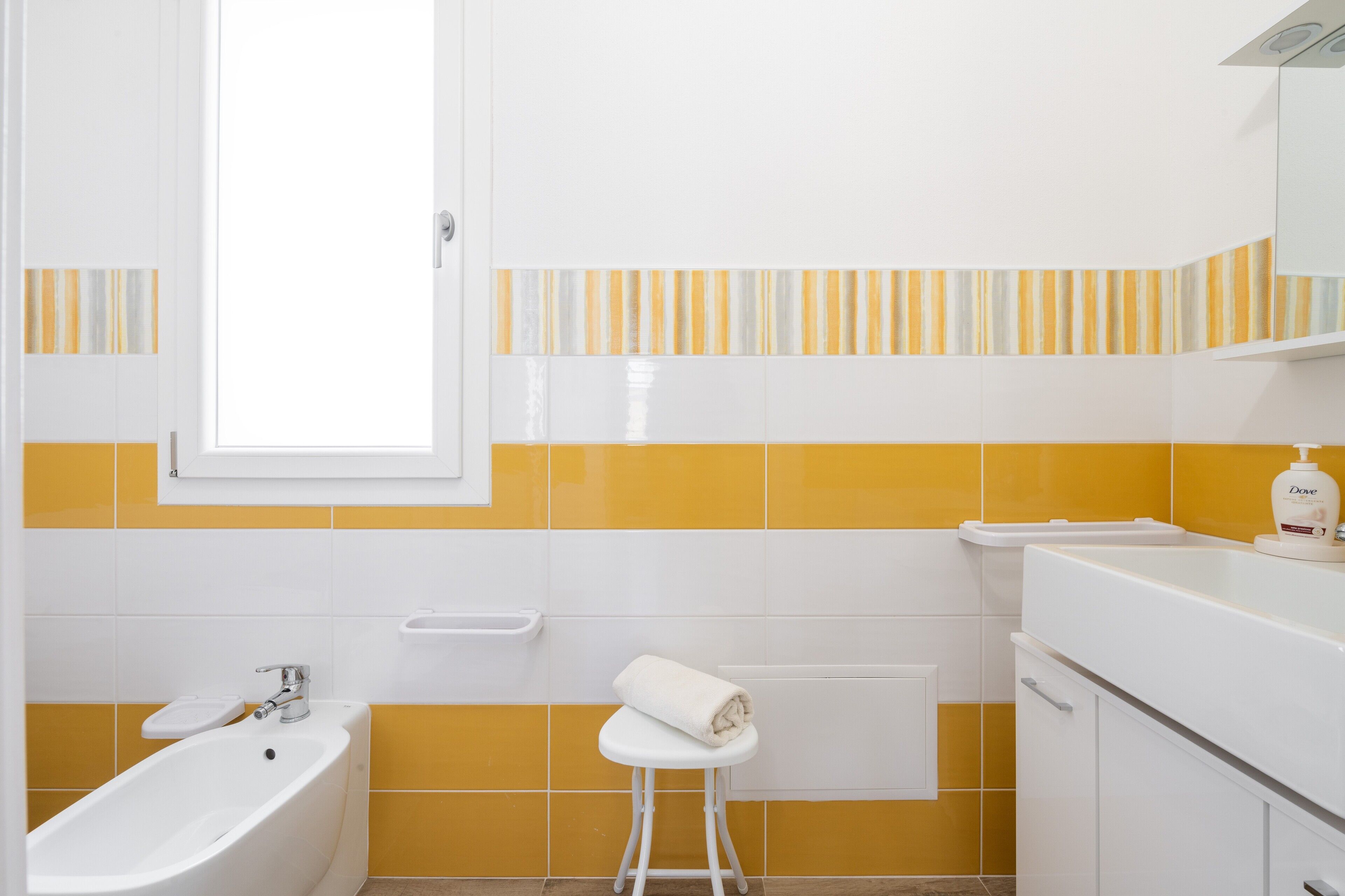 Un bagno con una vasca, un water, un lavandino e un asciugamano su uno sgabello.