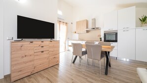 Une cuisine moderne avec un coin repas, des meubles en bois, un téléviseur à écran plat et un four encastré.