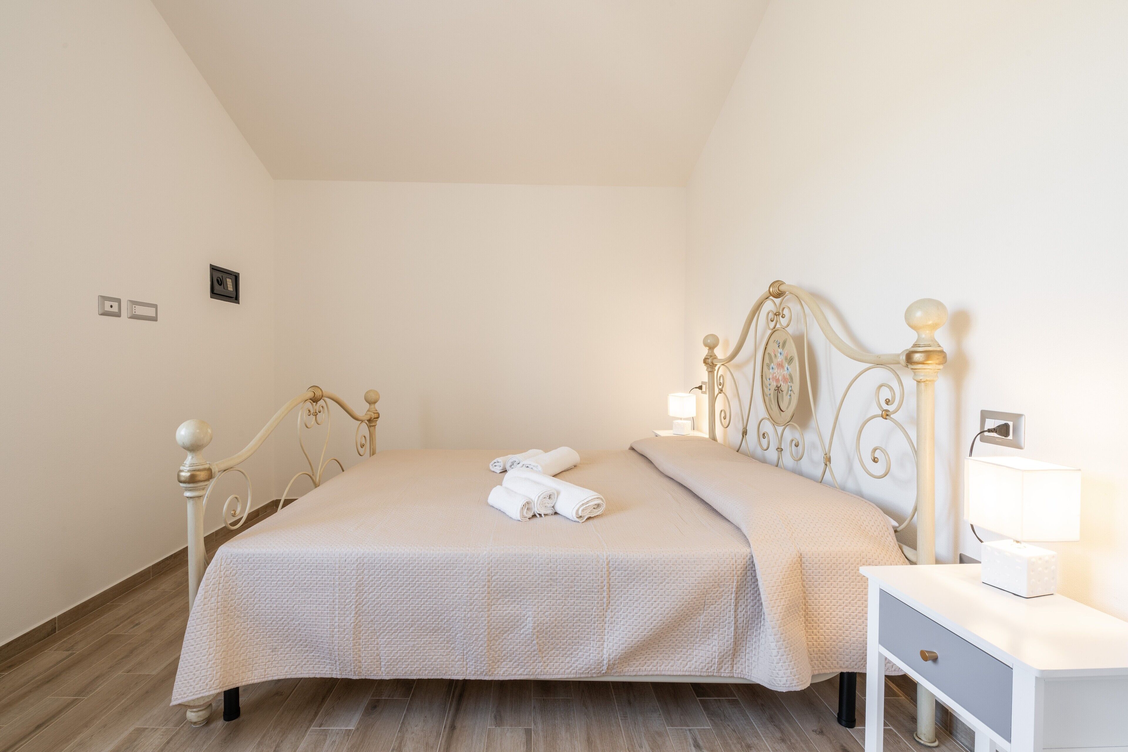 A neatly made bed with a headboard, bedside table, and lamp.