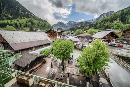 A traditional wooden building with a sloped roof, a covered outdoor seating area with tables and chairs, and a view of a mountain range in the background.. Apartment 'Apartment 3 in the Abbey - Maxit' with Wi-Fi