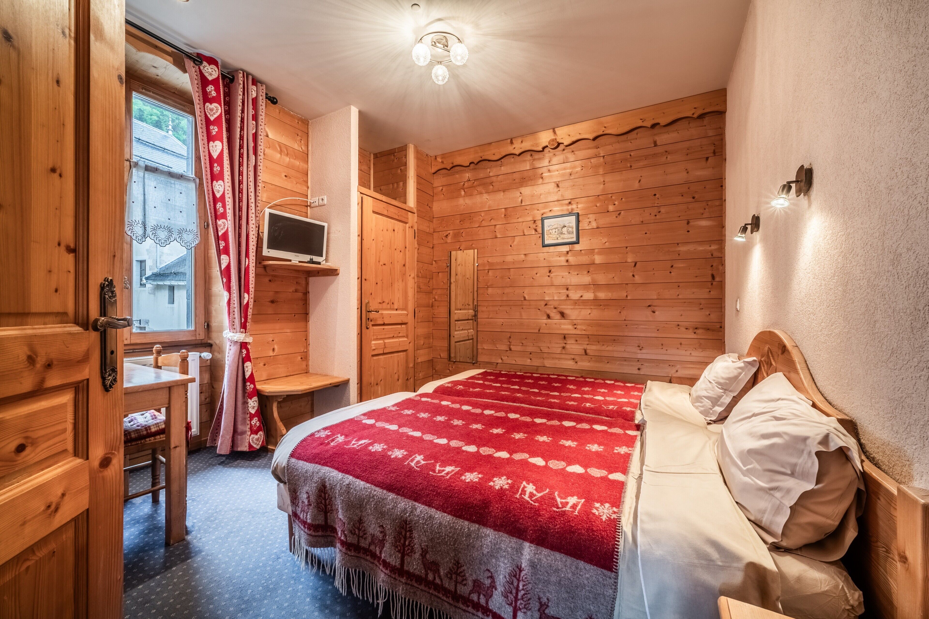 Une pièce en bois avec un lit, un bureau et un téléviseur.