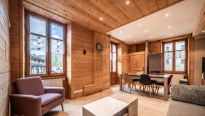 Un intérieur en bois comprenant un canapé, une table basse, un coin repas et une cuisine.