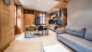 Une cuisine moderne avec des murs en bois, un coin repas avec des chaises, un canapé et une horloge au mur.