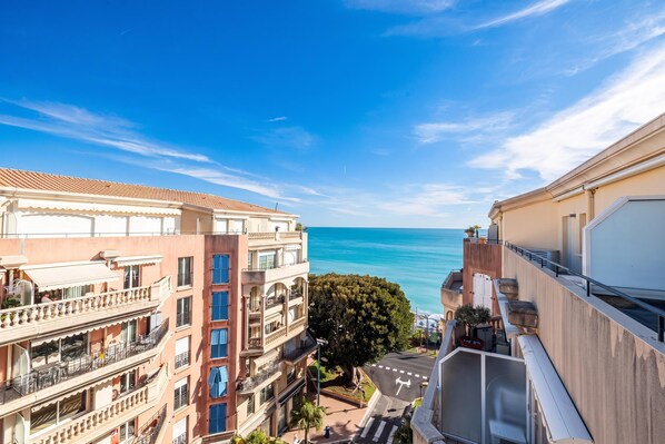 A coastal building with balconies, a clear sky, and a view of the sea.