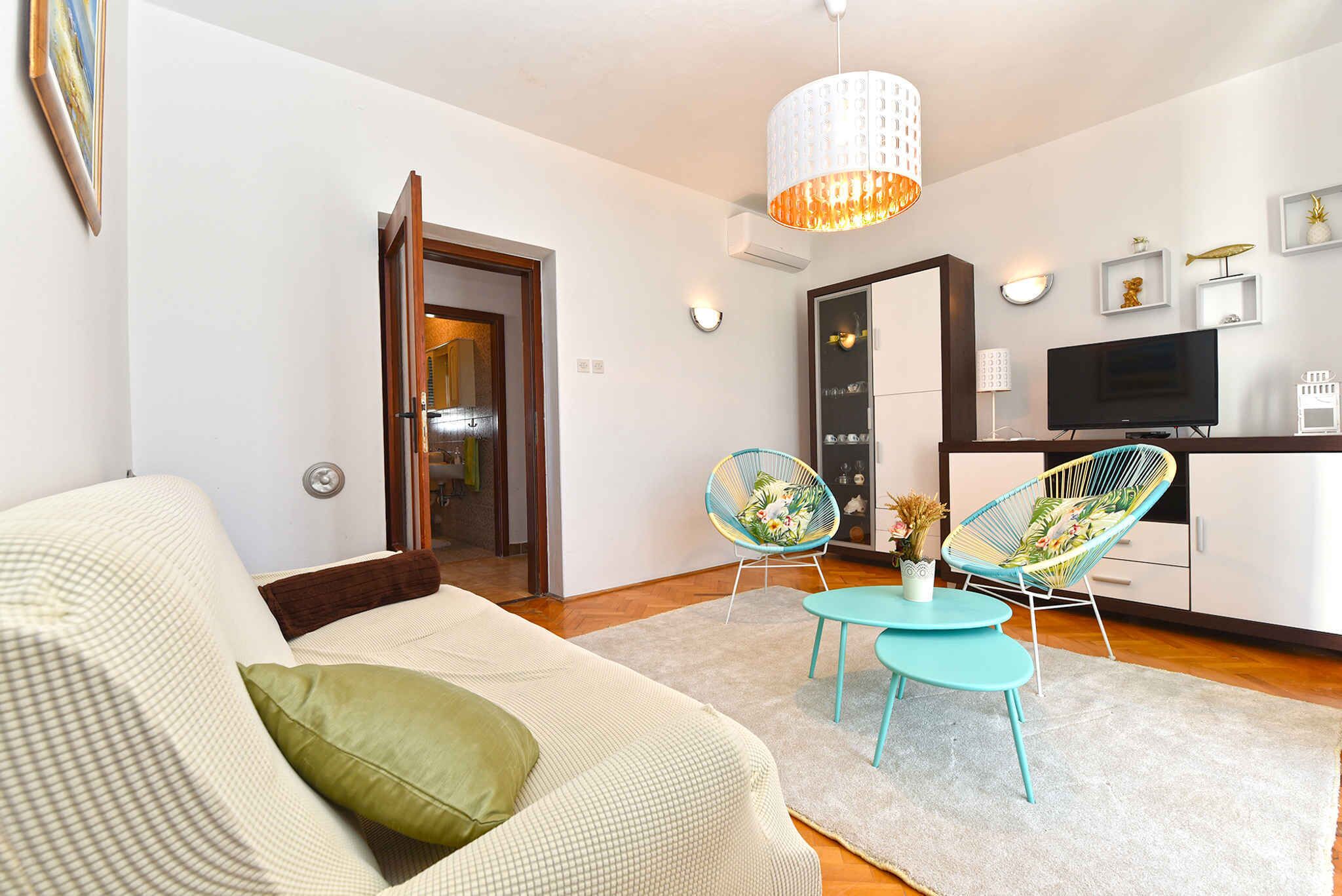 A modern living room with a sofa, two chairs, a coffee table, a TV, and a dining area.