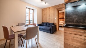 A modern kitchen with a built-in stove, wooden cabinets, and a dining area with a table and chairs. - Studio 2 Coeur d'Abondance-Maxit Apartment with Wi-Fi (Abondance)