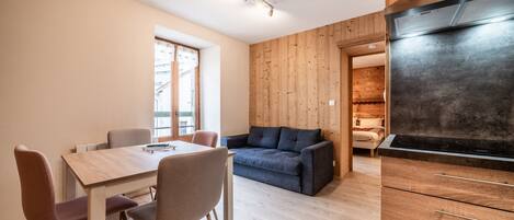 A modern kitchen with a built-in stove, wooden cabinets, and a dining area with a table and chairs.