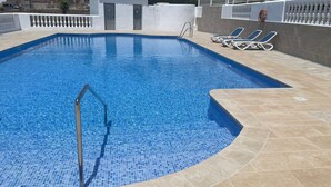 A swimming pool with a tiled edge, a metal ladder, and lounge chairs. - Apartment 'Bellavista Beach Club' with Sea View, Wi-Fi and Air Conditioning (Torrox Costa)