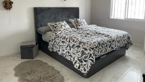 A bedroom with a bed, pillows, a rug, a small trash bin, and a wall decoration. - Apartment 'Bellavista Beach Club' with Sea View, Wi-Fi and Air Conditioning (Torrox Costa)