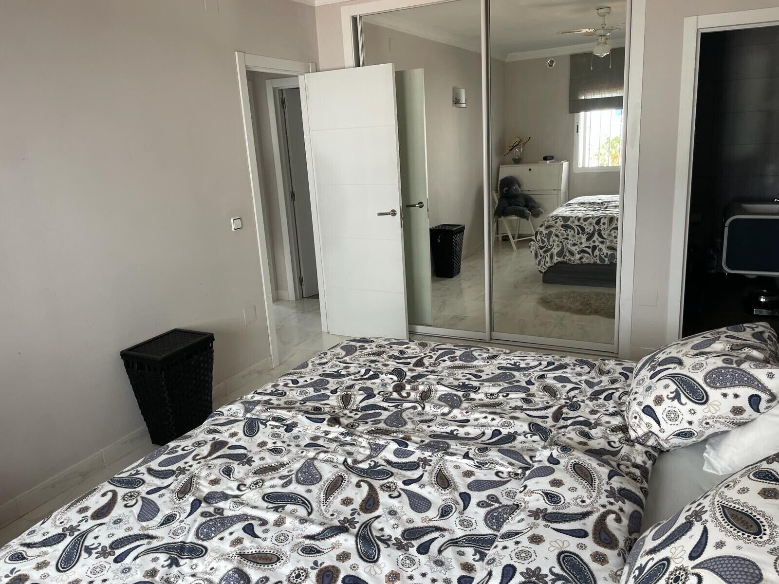 Une chambre à coucher avec un lit, une armoire, un miroir et un téléviseur.