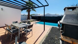 A patio with a pool, outdoor furniture, a grill, and a view of the mountains. - Vacation Home 'Casa Rosa' with Mountain View, Private Pool and Wi-Fi (Playa Blanca)
