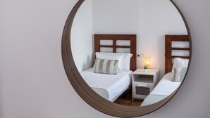 A circular mirror reflecting a bedroom with two beds, a bedside table with a lamp, and a small plant. - Vacation Home 'Casa Rosa' with Mountain View, Private Pool and Wi-Fi (Playa Blanca)
