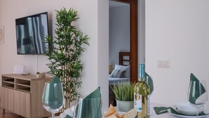 A dining area with a table set for two, a bottle of wine, a bowl of bread, and a green plant. - Vacation Home 'Casa Rosa' with Mountain View, Private Pool and Wi-Fi (Playa Blanca)