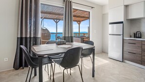A modern kitchen with a dining area, large windows, and a view of the sea.