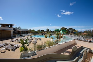 A resort pool area with lounge chairs, a water slide, and a view of the surrounding landscape. - Bungalow 'Ile D'or Parcelle Victor Hugo 1' with Sea View, Shared Pool and Private Terrace (Saint-Raphaël)
