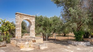 Une arche en pierre à l’extérieur, une cour dallée et une végétation luxuriante tout autour.