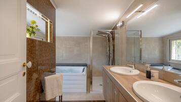 Une salle de bain moderne avec une baignoire, deux lavabos, une douche et un grand miroir.