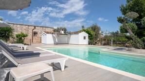 Une piscine avec des chaises longues et un bâtiment en pierre en arrière-plan.