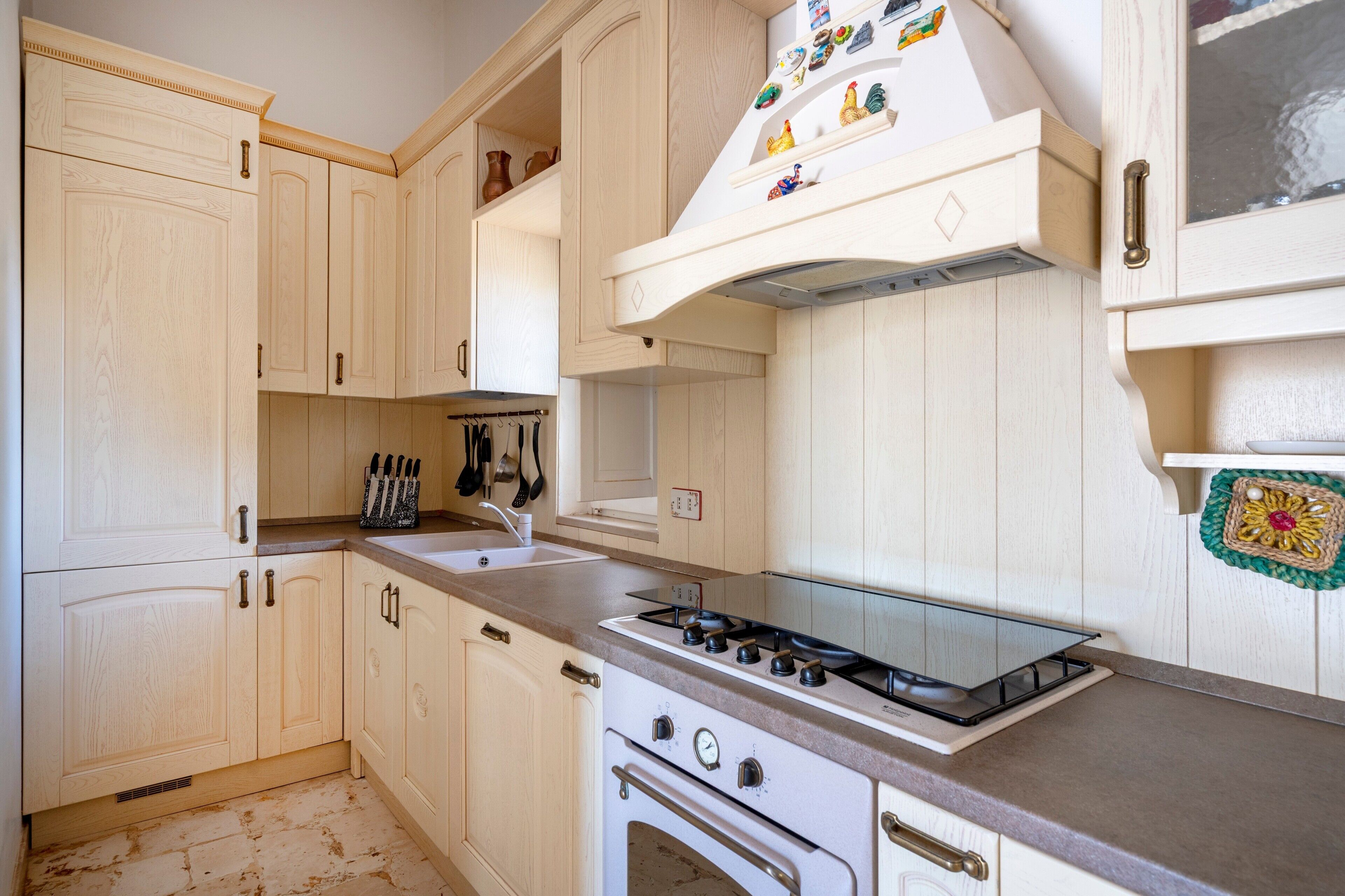 Une cuisine avec des meubles de rangement en bois clair, une cuisinière à gaz, un four et un évier.