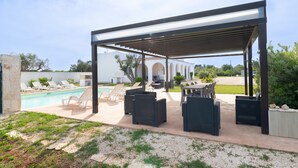 An outdoor patio with a pool, lounge chairs, and a covered seating area. - Villa 'Città Bianca' with Private Pool, Wi-Fi and Air Conditioning (Carovigno)