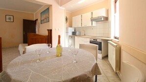 Un comedor con una mesa dispuesta para dos personas, una botella de vino y dos copas de vino.