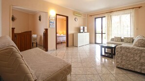 Habitación de hotel con cama, sofá, una mesita, televisor y baño visible a través de una puerta abierta.