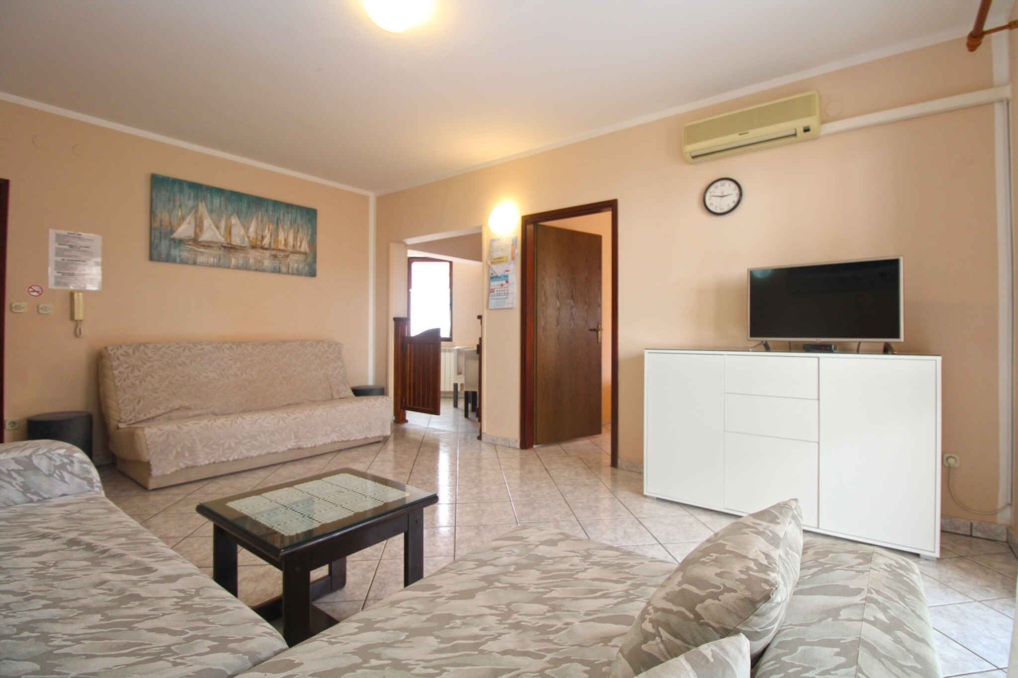 Una sala de estar con un sofá, una mesa de centro, un televisor sobre un mueble y un cuadro en la pared.